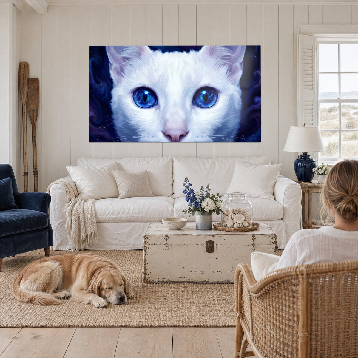 Cuadro gato blanco con iris azul cobalto en forma de estrella y hocico rosa pálido, colgado sobre un sofá en un salón luminoso con una persona de espaldas y un retriever