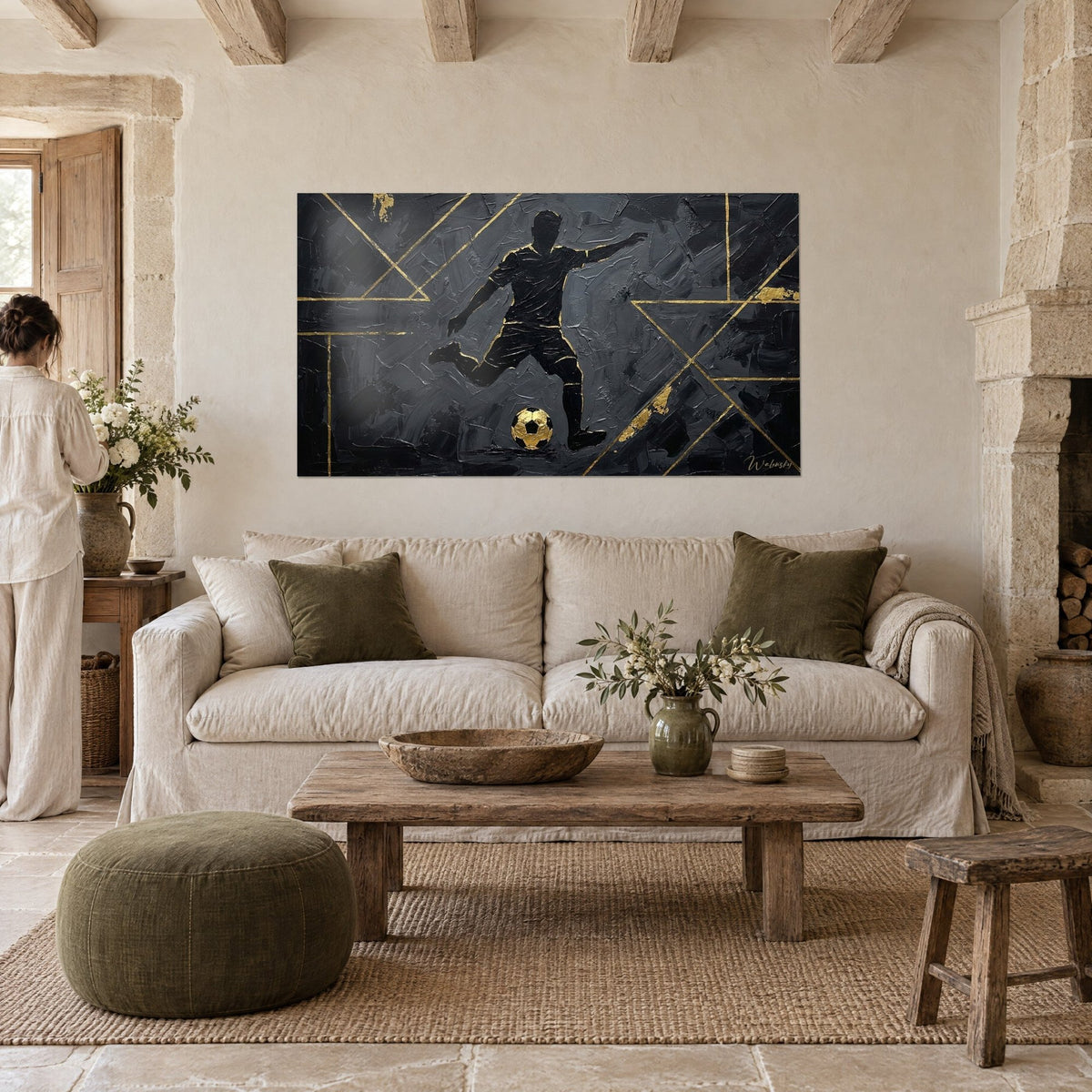 Tableau joueur de foot en silhouette noire frappant un ballon doré, traits dorés sur fond anthracite, au-dessus d'un canapé dans un salon lumineux