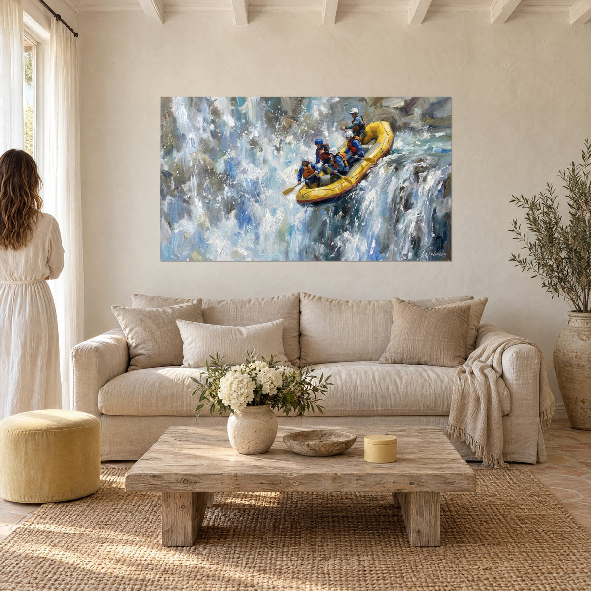 Wall art yellow raft tumbling down a cascade of white and blue foam, helmeted rowers, above a sofa in a bright living room