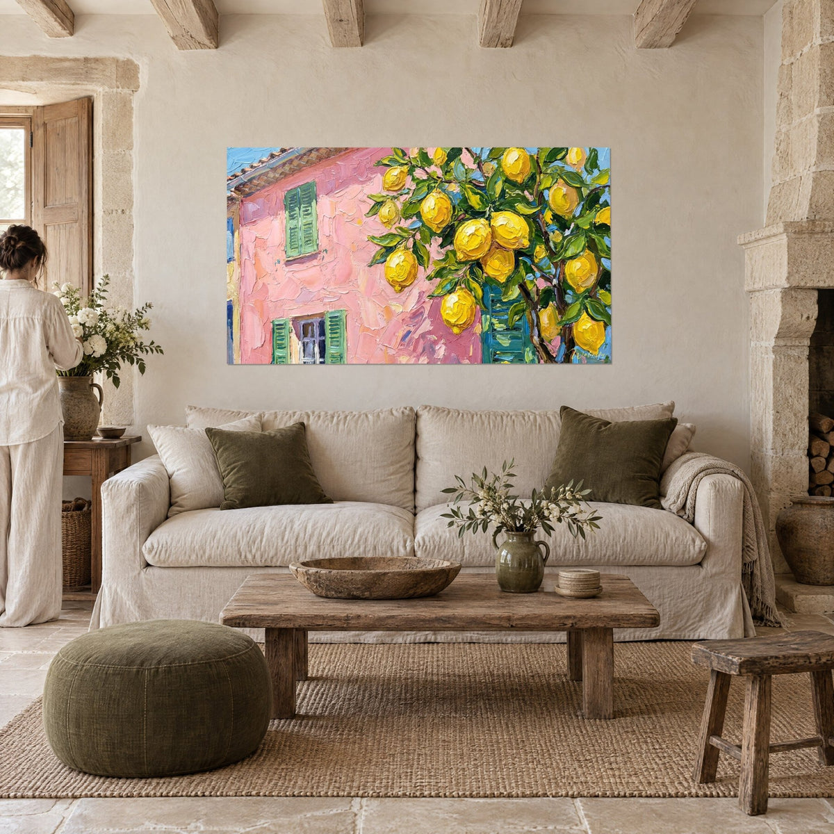 Wall art pink facade with green shutters beneath yellow lemons, a woman seen from behind, above a sofa in a bright living room