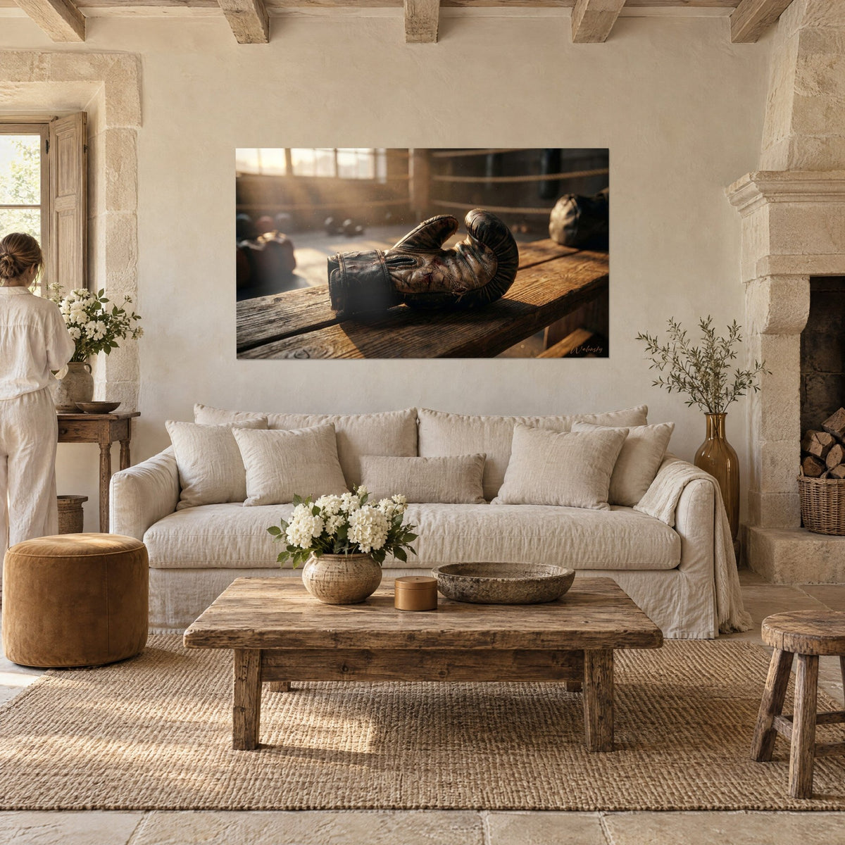 Wall art brown cracked leather boxing glove on wooden bench, red stains, golden light; two people seen from behind above a sofa in a bright living room