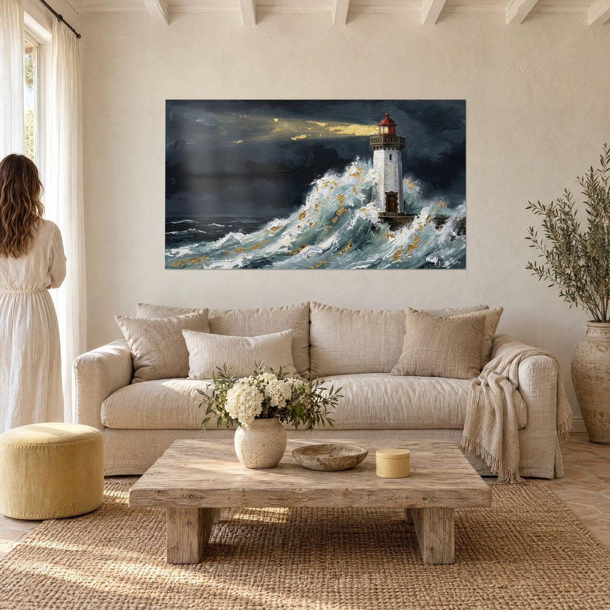 Quadro faro bretone con lanterna rossa sotto un cielo d'inchiostro, onda bianca e dorata, donna di spalle, sopra un divano in un soggiorno luminoso