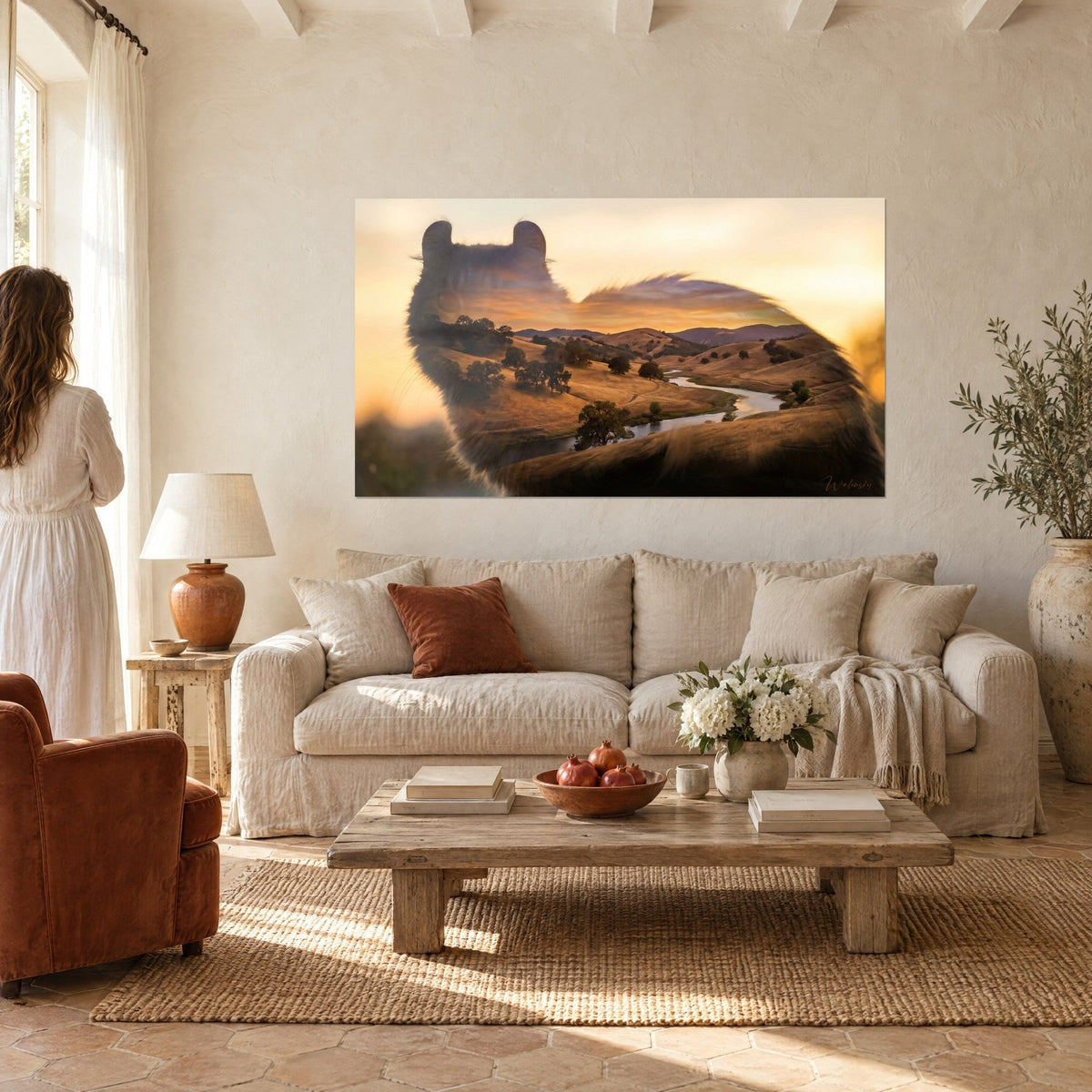 Schilderij silhouet van een American Curl kat gevuld met gouden heuvels en een rivier, vrouw van achteren, boven een bank in een lichte woonkamer