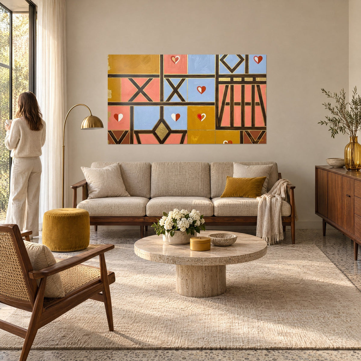 Wall art with stylized Alsatian half-timbered houses in salmon pink, sky blue and ochre, brown beams and hearts, above a sofa in a bright living room