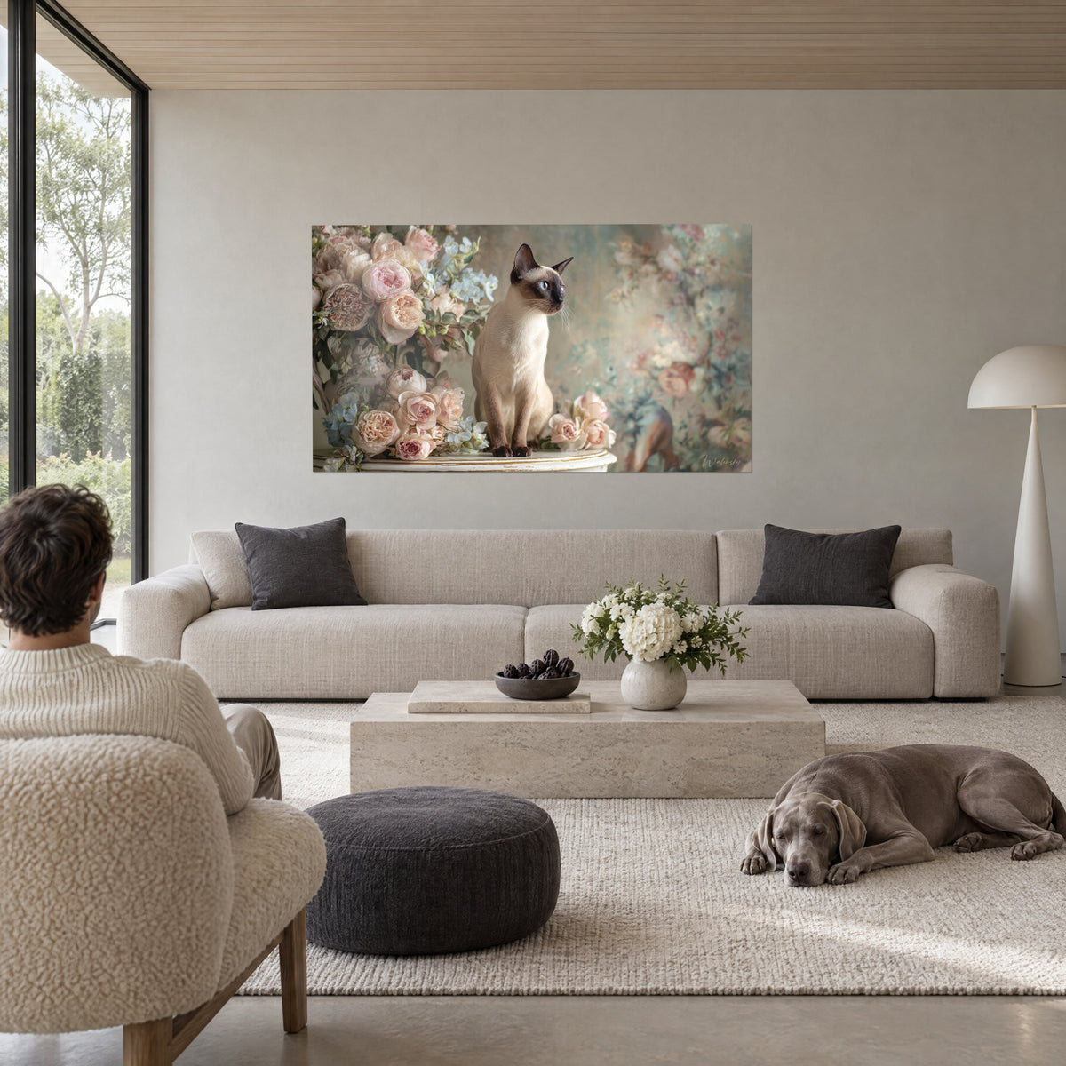 Tableau chat balinais aux yeux bleus, perché parmi des pivoines rose poudré et ivoire, au-dessus d'un canapé dans un salon lumineux