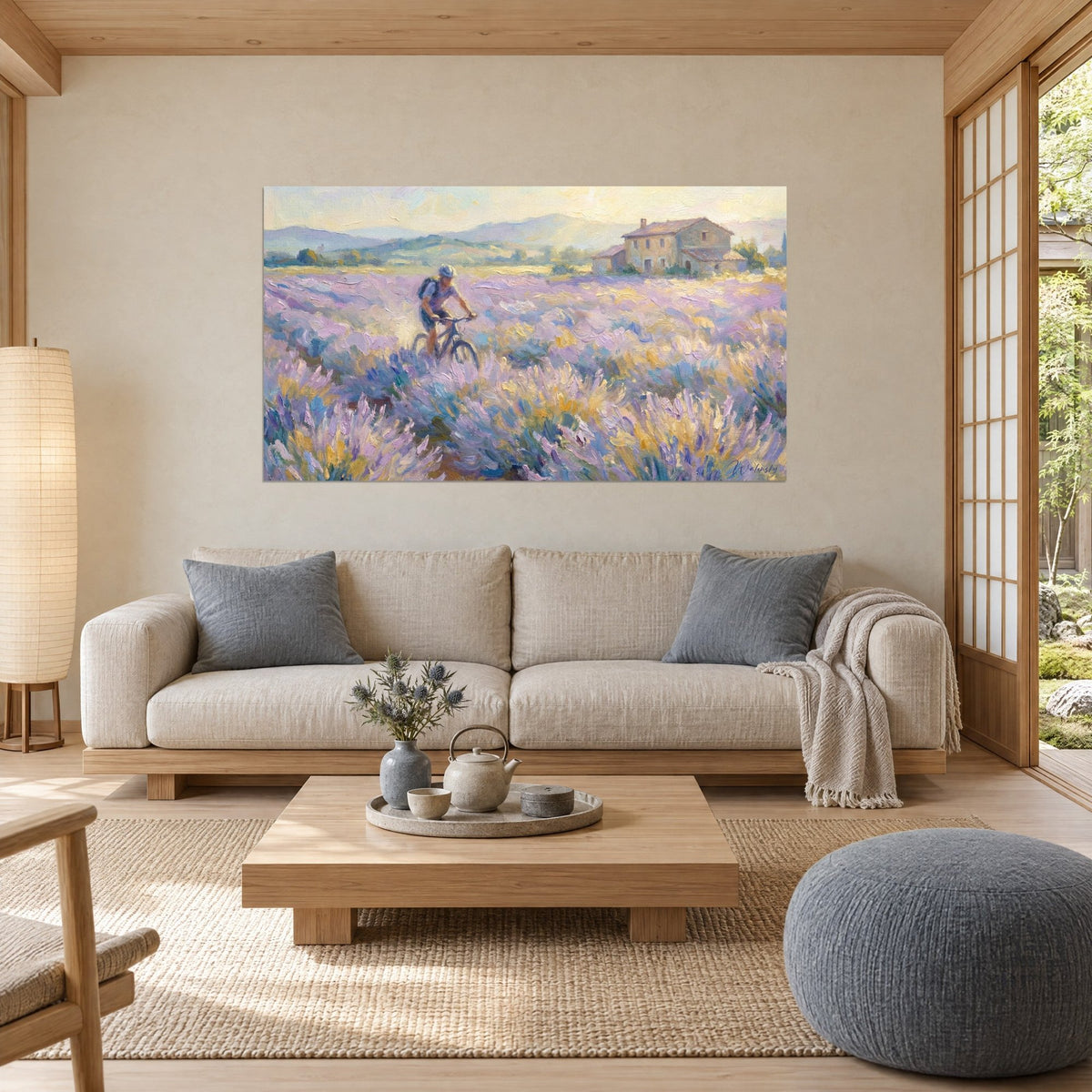 Tableau cycliste en casque bleu pédalant dans un champ de lavande mauve et or, ferme en pierre, au-dessus d'un canapé dans un salon lumineux