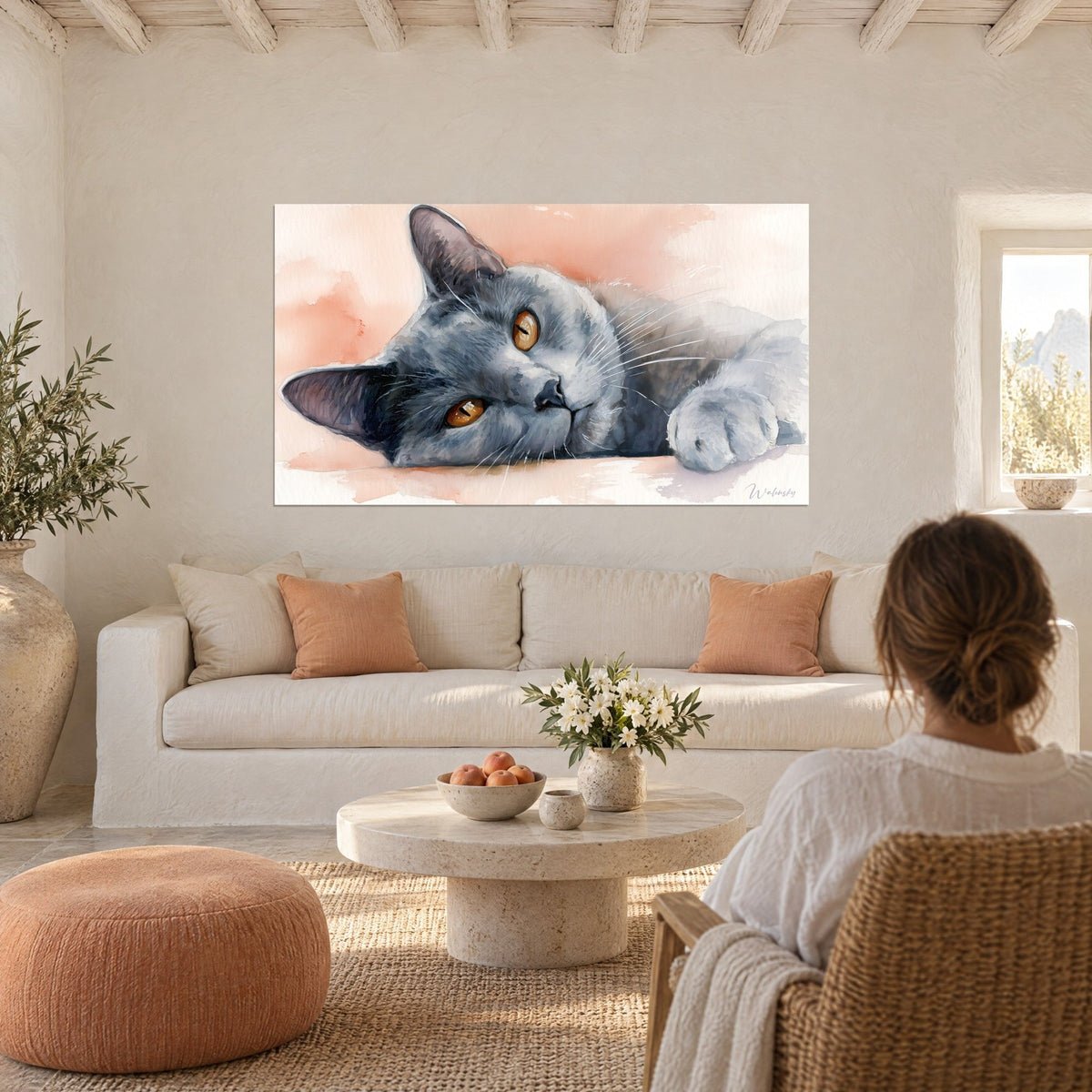 Tableau chat chartreux gris-bleu allongé, yeux ambrés, fond aquarelle rose saumon, au-dessus d'un canapé dans un salon lumineux