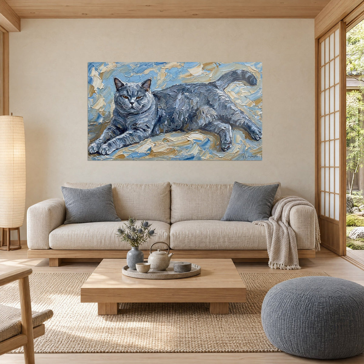 Gemälde einer graublauen Katze, ausgestreckt liegend, Fell in pastosen Strichen, blauer und cremebeiger Hintergrund, über einem Sofa in einem hellen Wohnzimmer