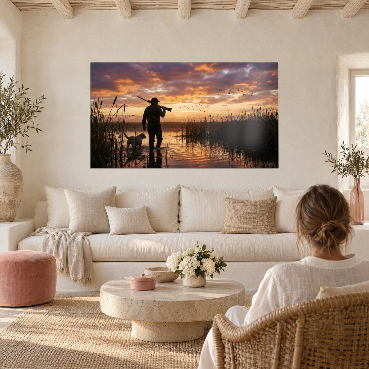 Quadro cacciatore in silhouette, fucile in spalla, cielo arancio e viola sopra una palude, sopra un divano in un soggiorno luminoso