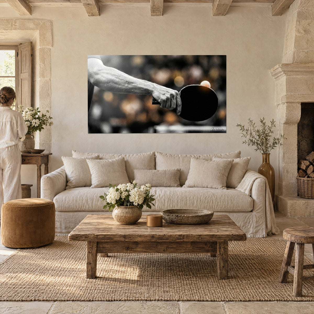 Tableau avant-bras veineux serrant une raquette noire, balle orange en suspens, bokeh doré, noir et blanc, au-dessus d'un canapé dans un salon lumineux