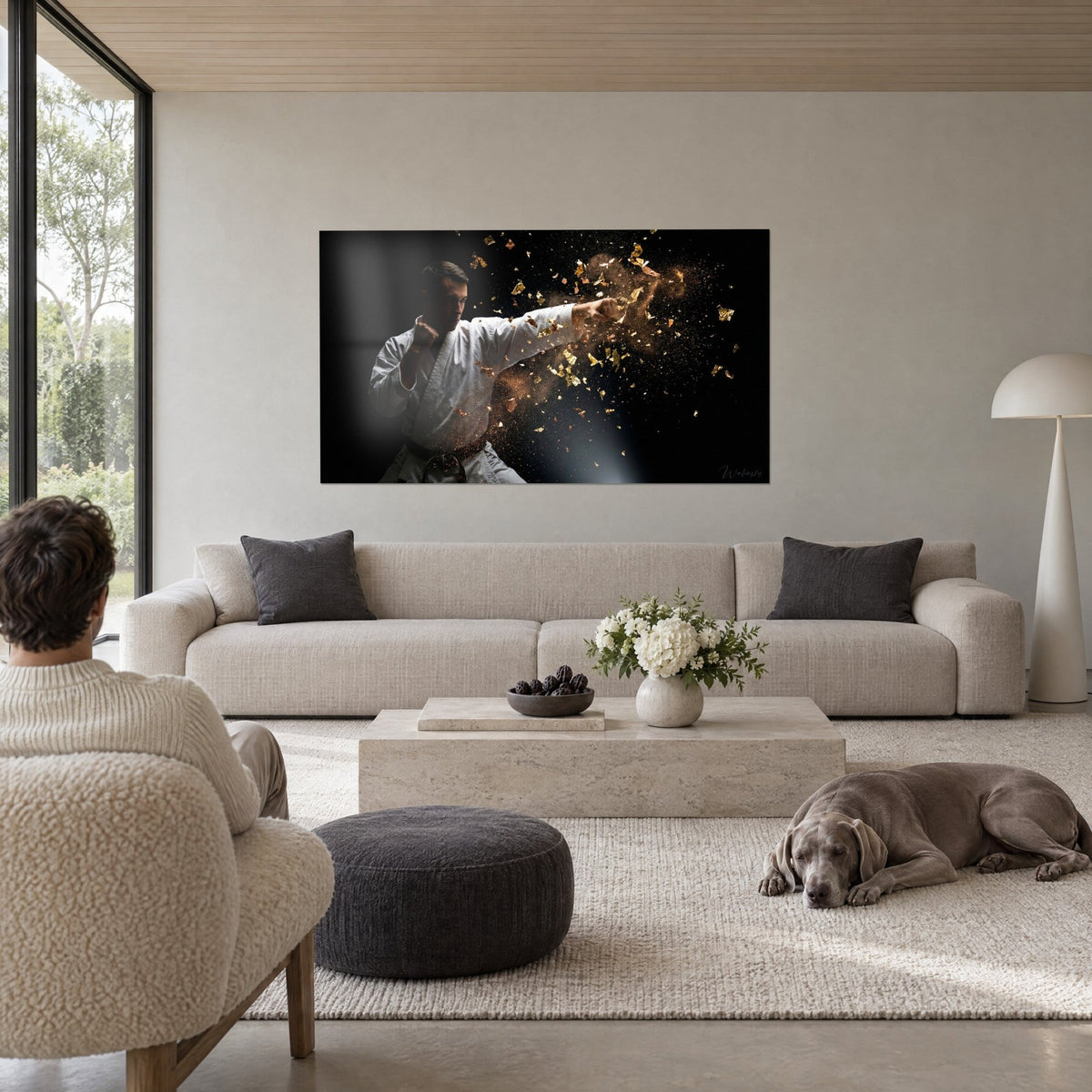 Tableau karatéka en kimono blanc lançant un coup de poing dans une gerbe de paillettes dorées, au-dessus d'un canapé dans un salon lumineux