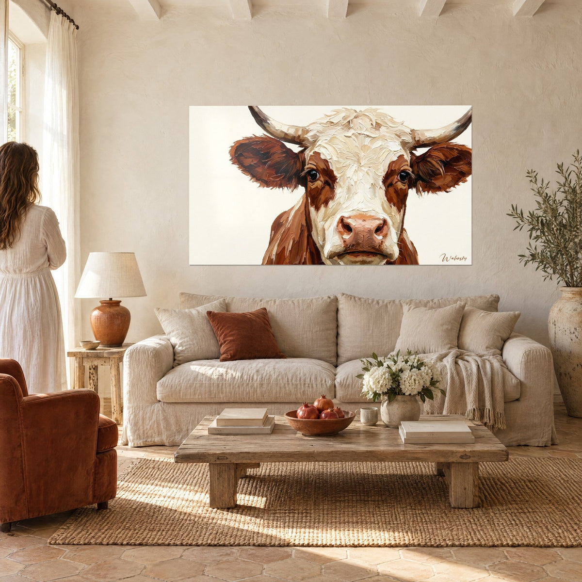 Gemälde Kuh mit braunem Fell und elfenbeinfarbenen Hörnern, rosa Schnauze und dunklem Blick, Signatur Walensky, über einem Sofa in einem hellen Wohnzimmer