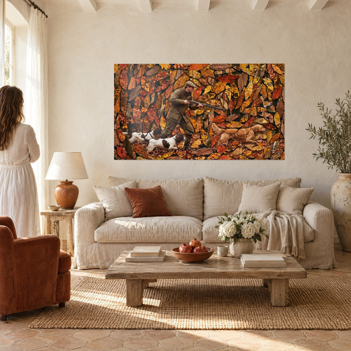 Wall art hunter in an olive jacket shouldering his rifle, dogs running through a patchwork of orange leaves, above a sofa in a bright living room