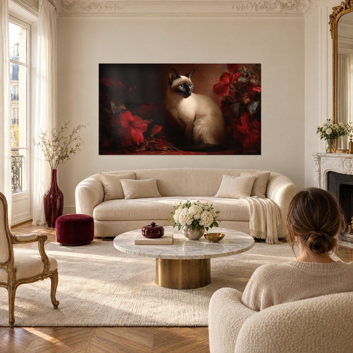 Tableau chat siamois aux yeux bleus assis parmi des hibiscus rouge carmin sur fond brun, au-dessus d'un canapé dans un salon lumineux