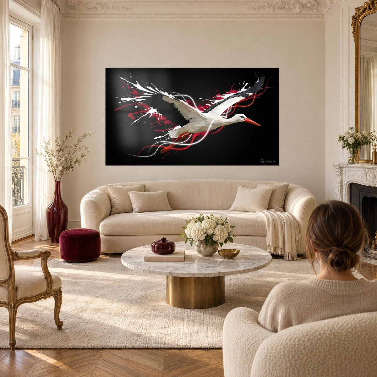 Wall art white stork in full flight, black wings, red splashes on a dark background, above a sofa in a bright living room