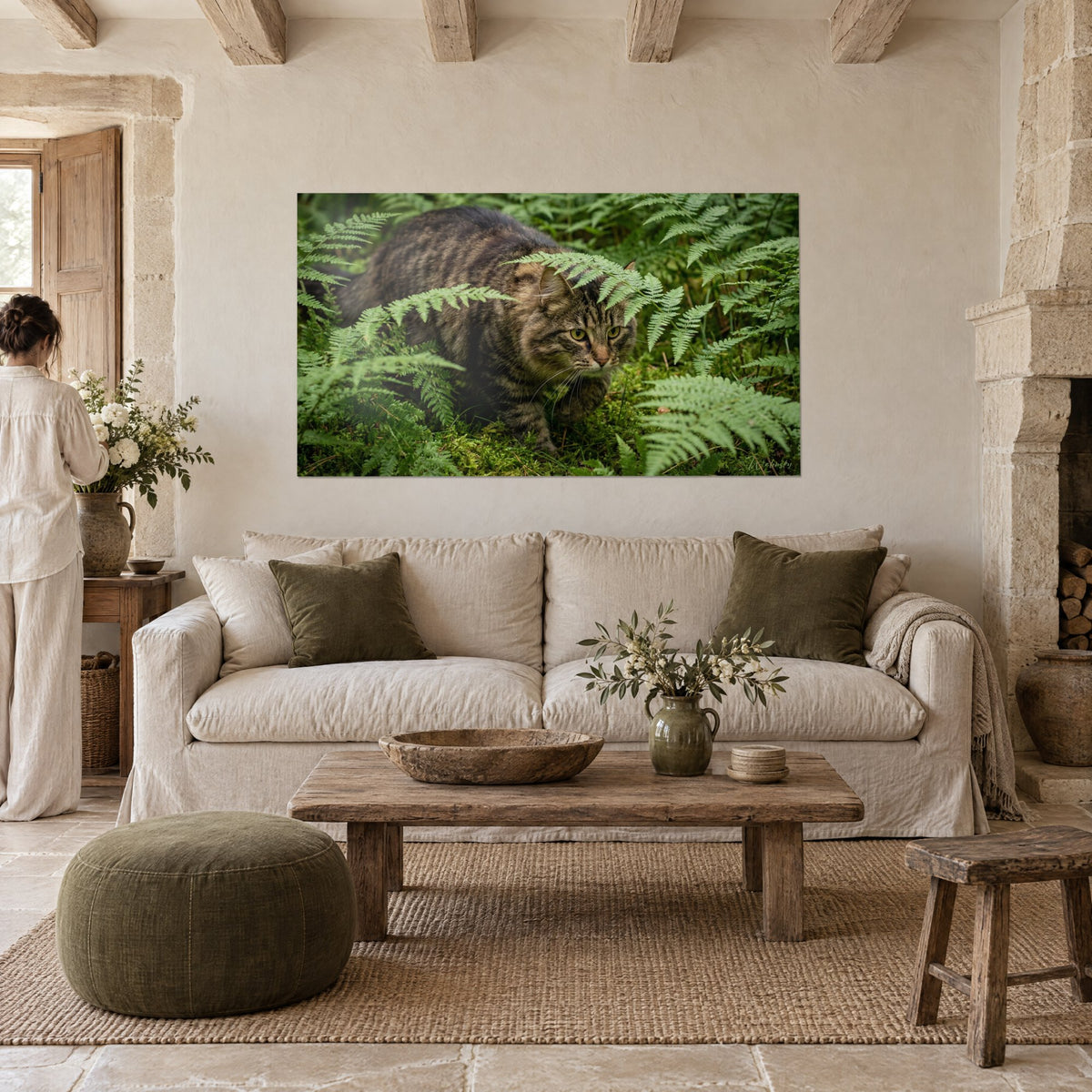 Wall art of a brown and grey tabby Norwegian Forest Cat among vivid green ferns, above a sofa in a bright living room