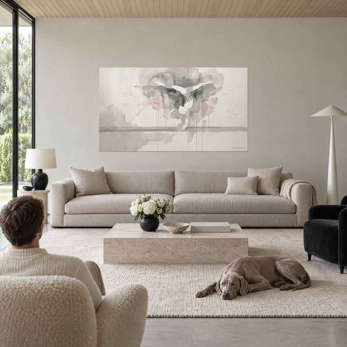 Gemälde Turnerin in freier Schwebe, graue und rosa Farbtropfen, die auf cremefarbenem Grund zerlaufen, über einem Sofa in einem hellen Wohnzimmer