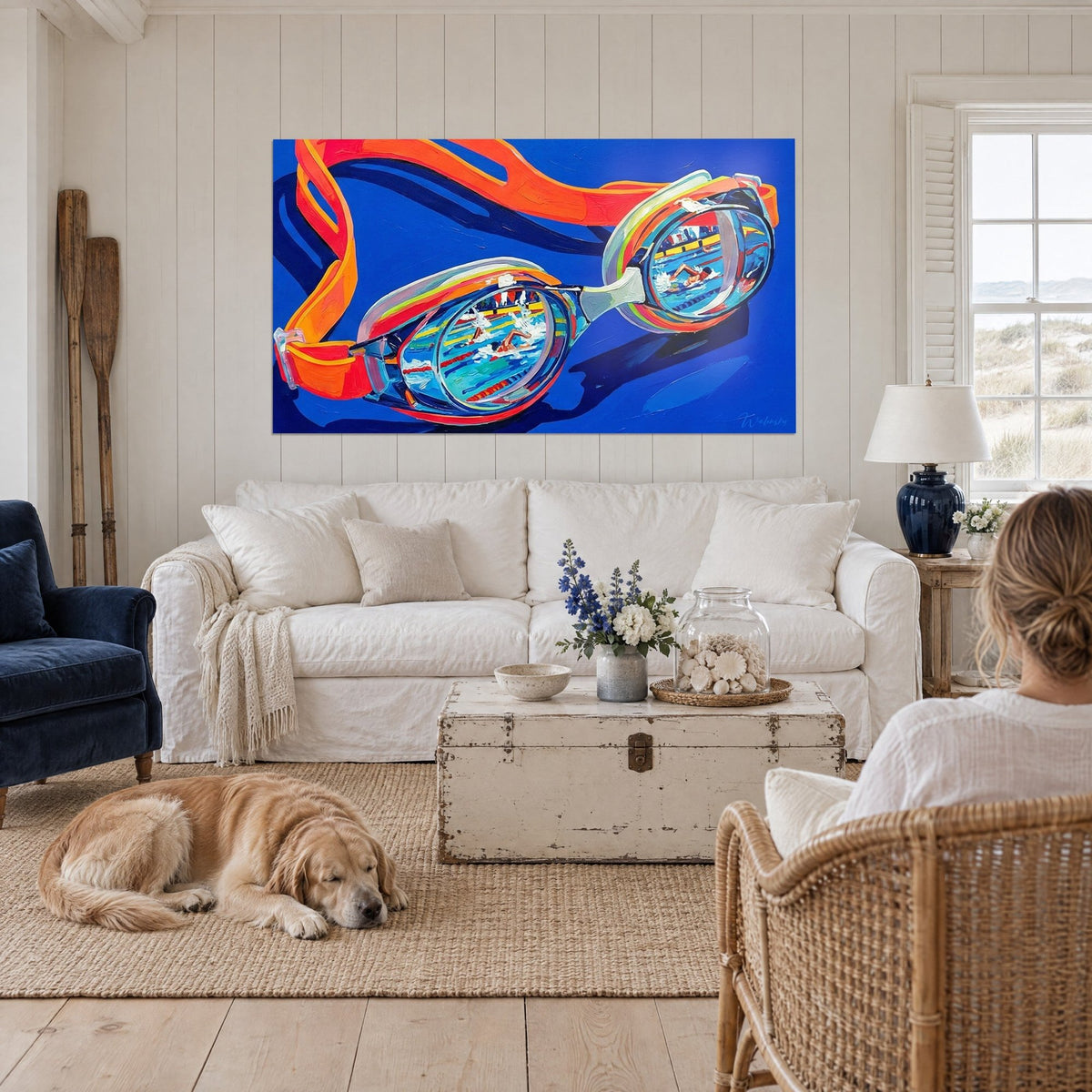 Tableau paire de lunettes de piscine orange et bleu cobalt, nageur en crawl reflété, au-dessus d'un canapé dans un salon lumineux