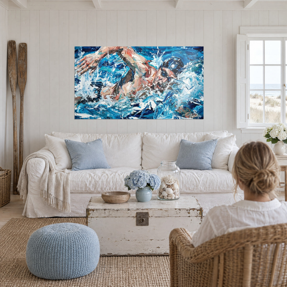 Quadro di un nuotatore a crawl che fende l'acqua, braccio rosa e cuffia nera su sfondo blu cobalto, sopra un divano in un soggiorno luminoso