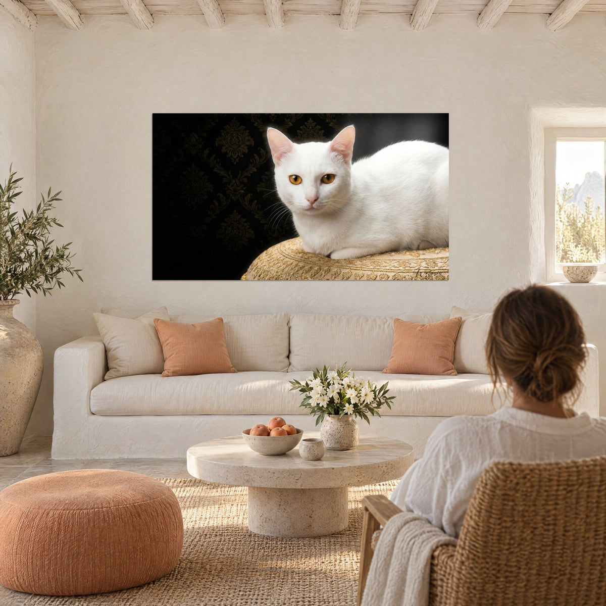 Gemälde weiße Katze mit bernsteinfarbenen Augen, auf einem goldbestickten Kissen liegend, schwarzer Damasthintergrund, über einem Sofa in einem hellen Wohnzimmer