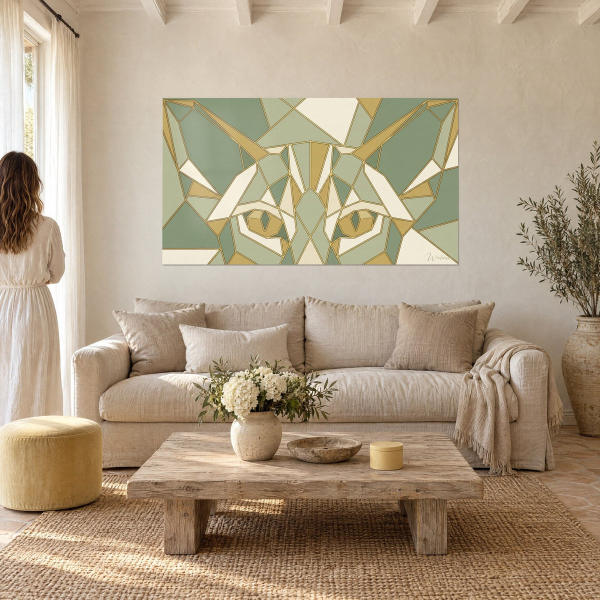 Wall art oriental cat in faceted sage green and gold ochre, yellow eyes, two people seen from behind, above a sofa in a bright living room