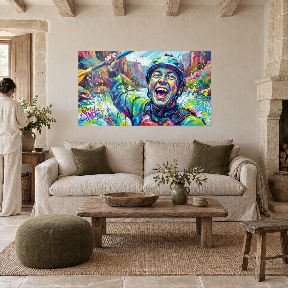 Wall art of a laughing rafter raising his paddle, blue helmet, lime green and pink splashes, hanging above a sofa in a bright living room
