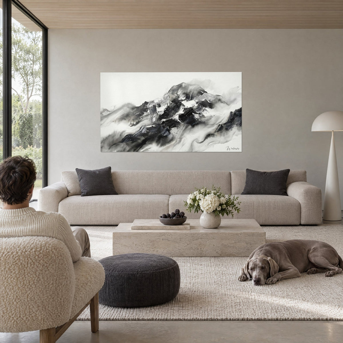Gemälde eines nebelverhangenen Schneegipfels, tintenschwarz und perlmuttweiß, zwei Personen von hinten, über einem Sofa in einem hellen Wohnzimmer