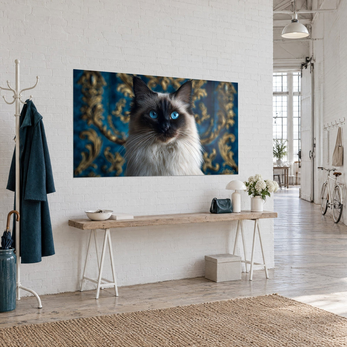 Tableau portrait félin au regard turquoise, museau sombre et fourrure ivoire devant des volutes d'or sur fond bleu, console en bois et murs blancs