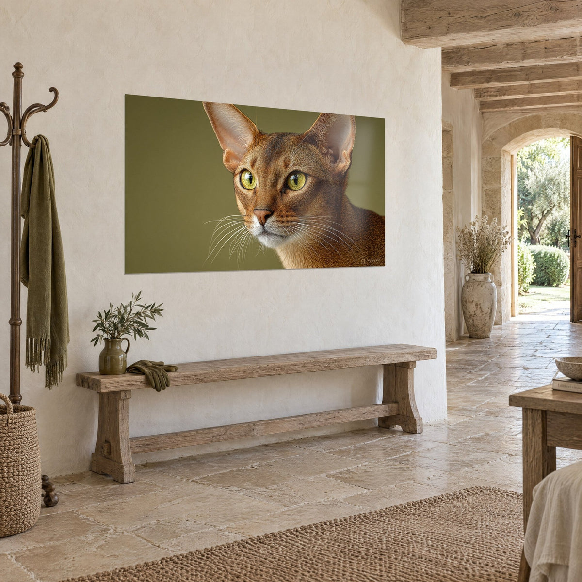 Tableau félin élancé aux grandes oreilles, museau blanc et fond vert olive, sur un mur crème dans une entrée en pierre
