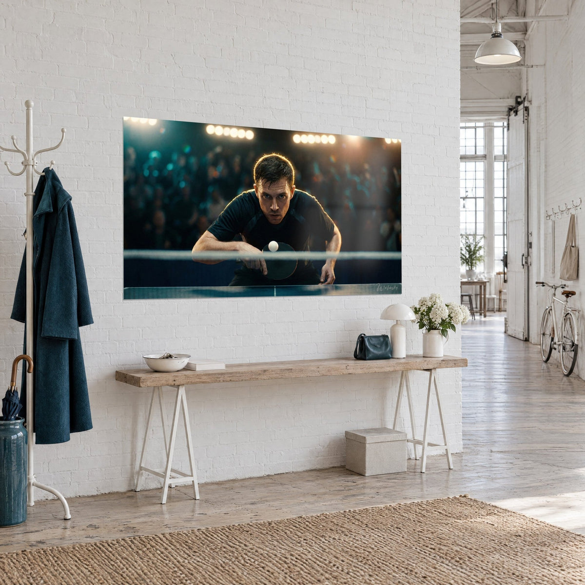 Wall art of a table tennis player leaning over the navy blue net, tense face, orange glow, white brick wall of a loft
