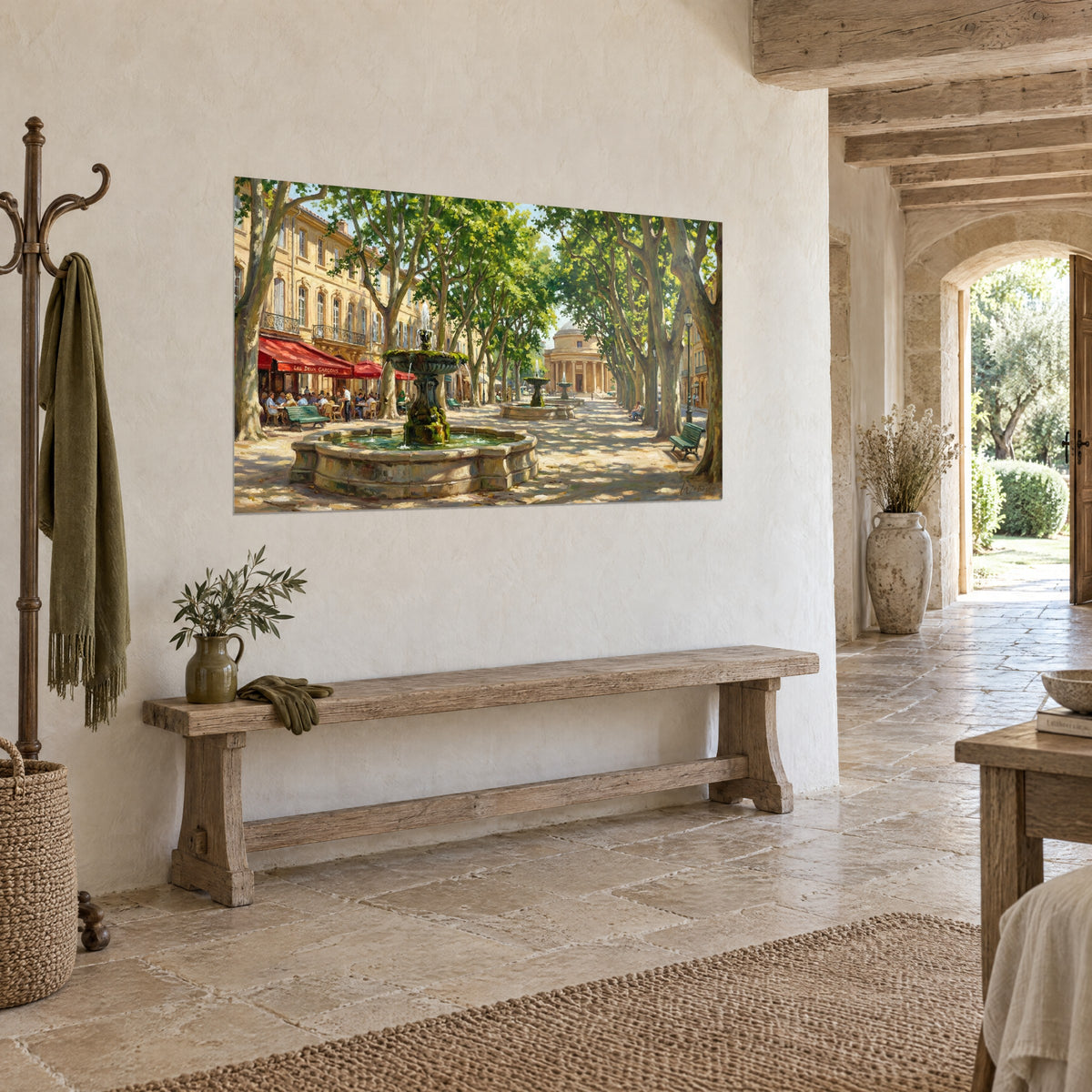 Tableau fontaine de pierre moussue sous les platanes verts, terrasse aux parasols rouges, mur blanc et banc rustique en vue de trois-quarts