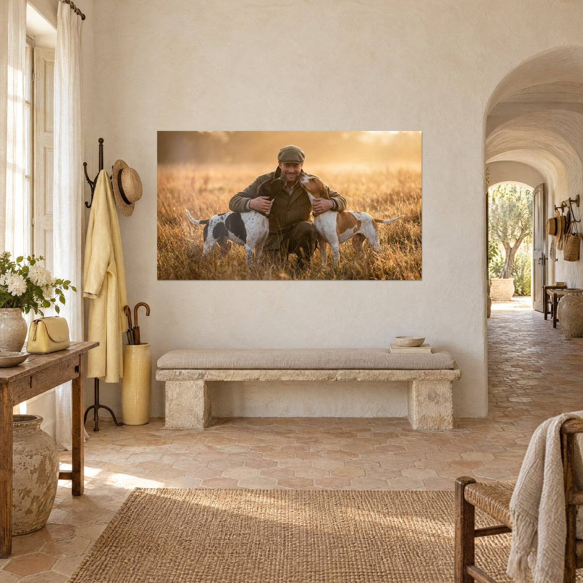 Quadro uomo sorridente con giacca verde che abbraccia due bracchi bianchi chiazzati di marrone, luce dorata, vista di tre quarti verso il masseria