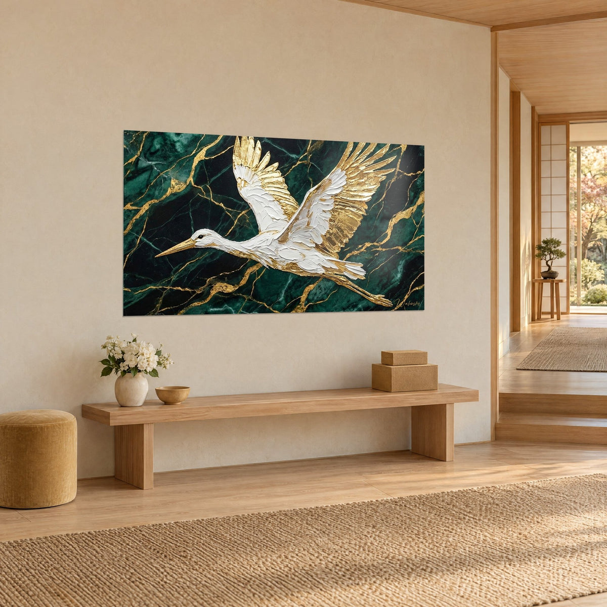 Wall art wading bird in flight, thickly textured white plumage and gold leaf wings on a dark green background, beige wall beside a wooden bench