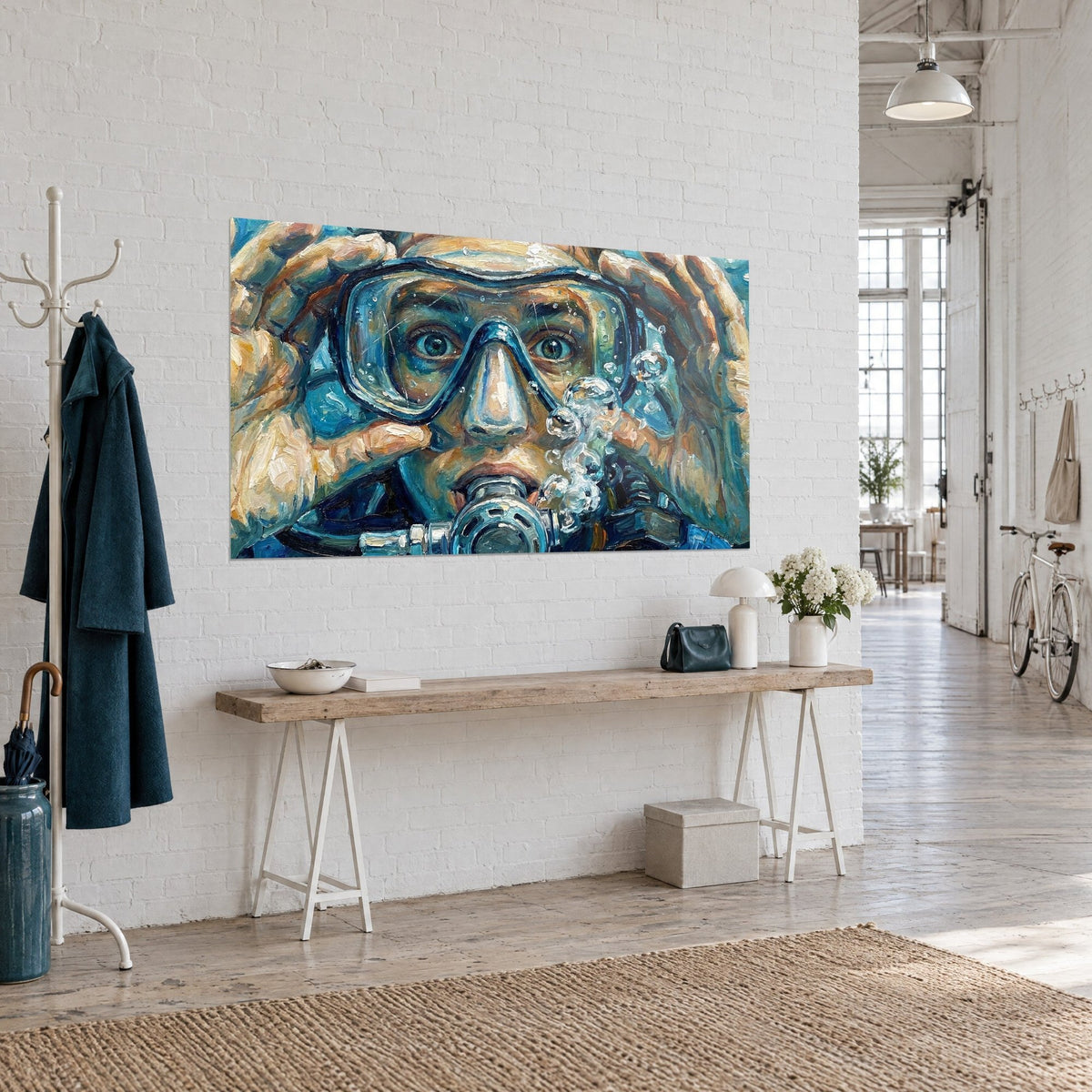 Wall art of a diver's face in a turquoise mask, thick ochre paint and gray regulator, on a white wall beside a console table