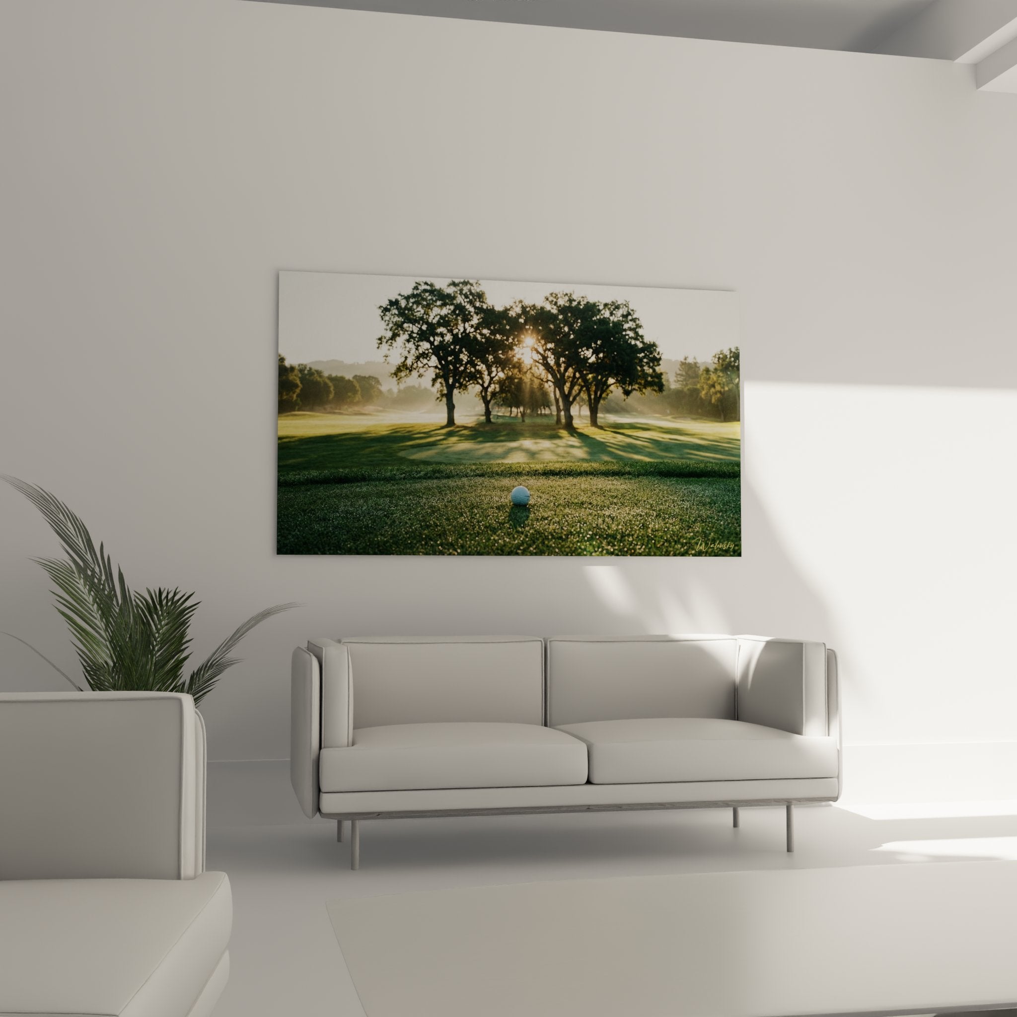 Détail balle de golf sur green avec rayons dorés du soleil levant filtrant à travers arbres majestueux