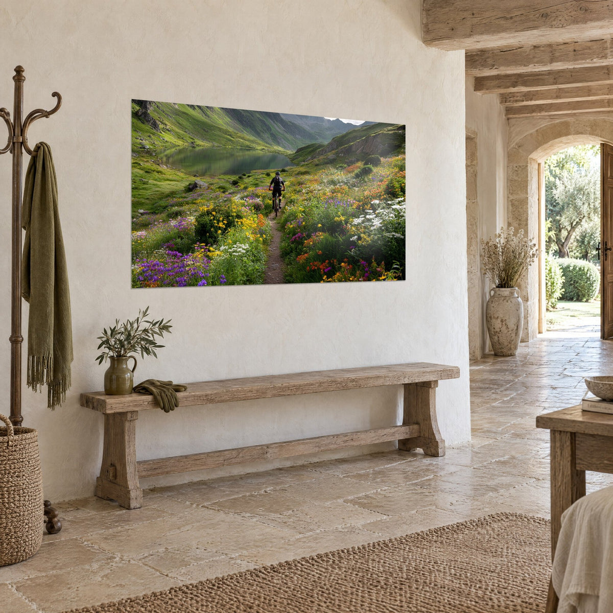 Wall art of a mountain biker riding between orange and white flowers, emerald lake in the background, hung on a stone wall, three-quarter view