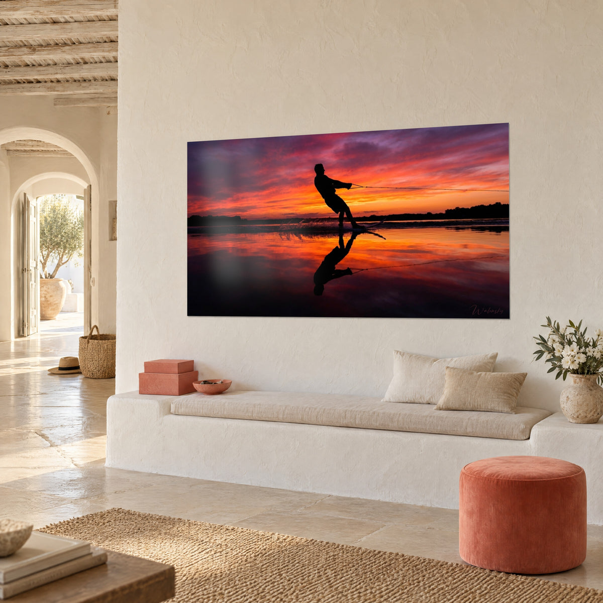 Quadro sagoma nera di un wakeboarder che tira la sua corda, nuvole rosse e porpora, muro intonacato di una casa mediterranea