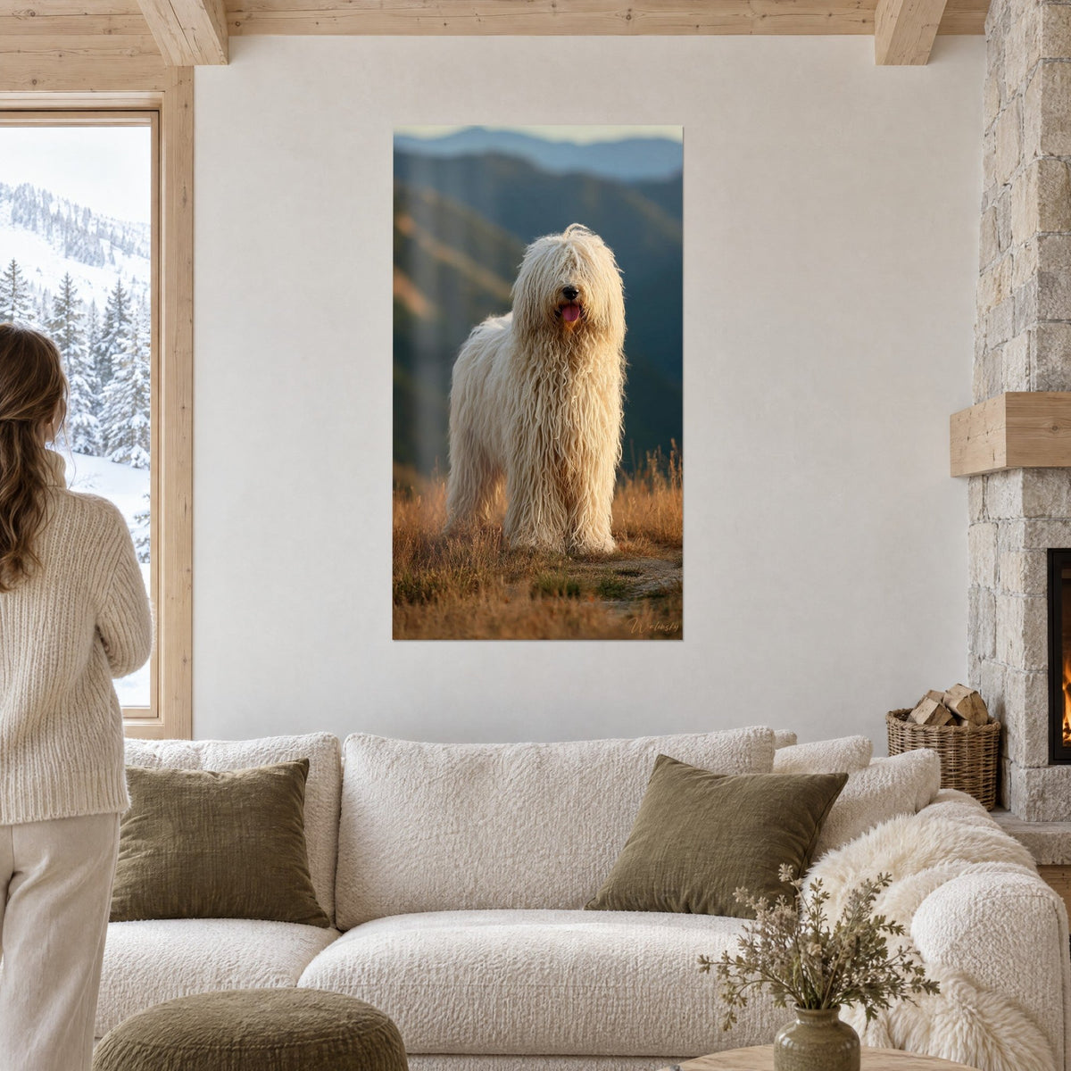 Cuadro de komondor con largos mechones crema sobre hierba dorada y montañas azuladas, encima de un sofá en un salón luminoso