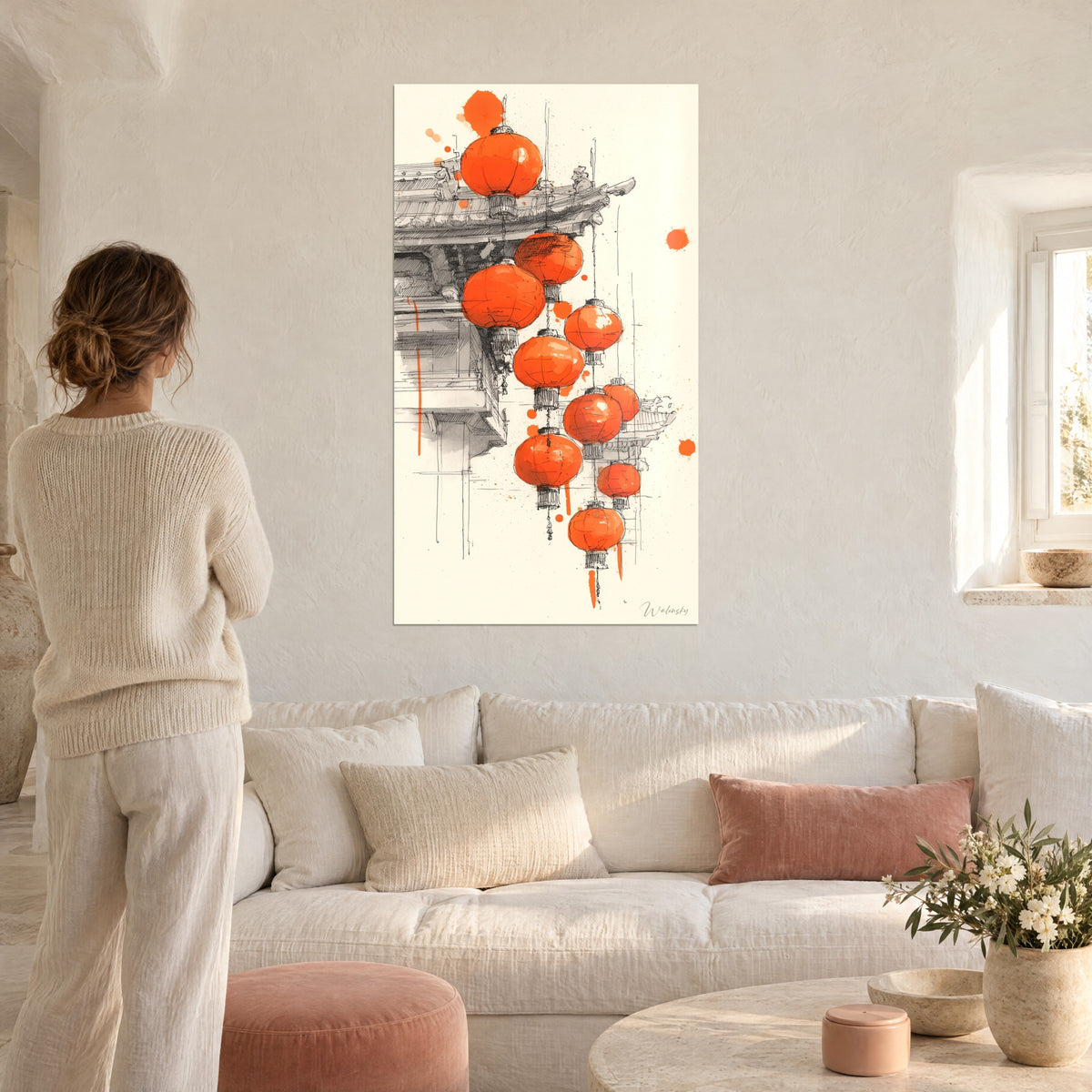 Wall art bright orange Chinese lanterns hanging beneath a pagoda roof outlined in black, woman seen from behind, above a sofa in a bright living room