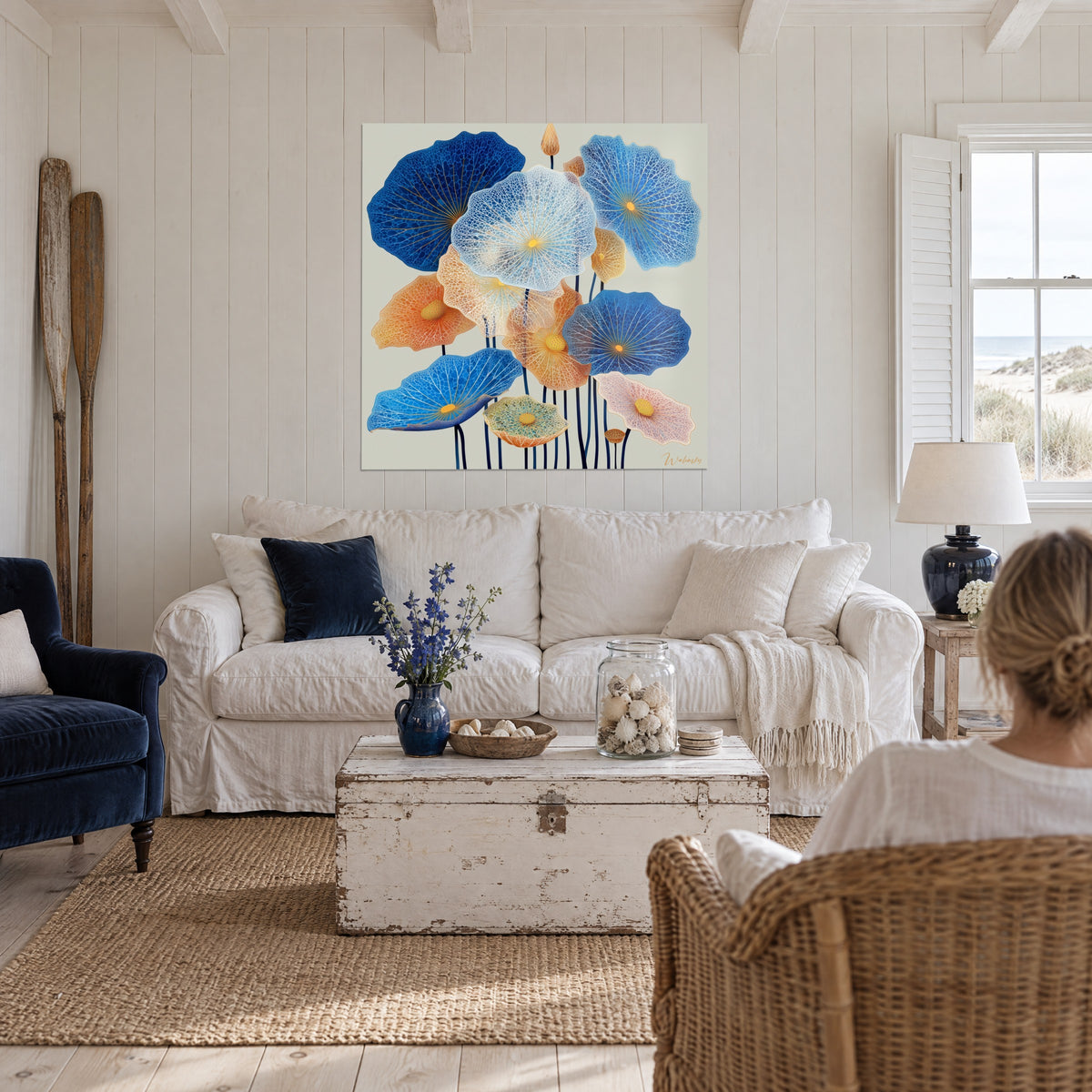 Quadro di ninfee blu cobalto e arancio con nervature dorate e foglie traforate, sopra un divano in un soggiorno luminoso
