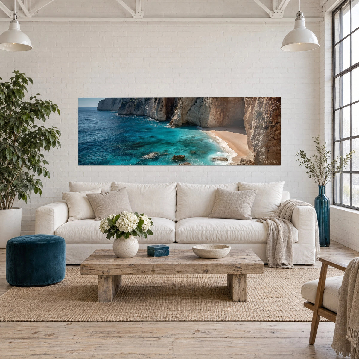 Wall art of a Mediterranean cove with turquoise waters and golden ochre cliffs, pale sand in a curve, above a sofa in a bright living room