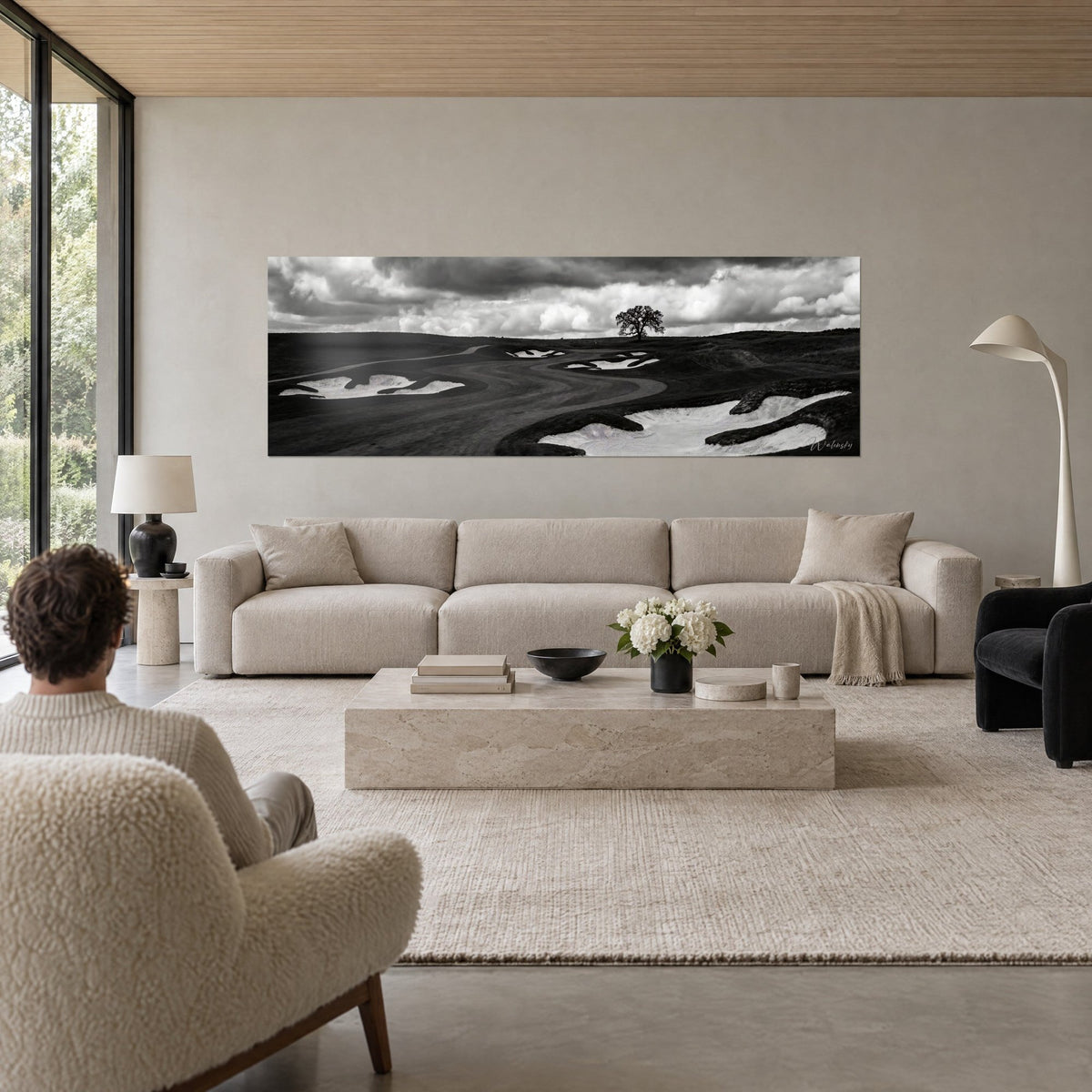 Wall art sinuous black-and-white fairway, pale sand bunkers and lone oak above a sofa in a bright living room
