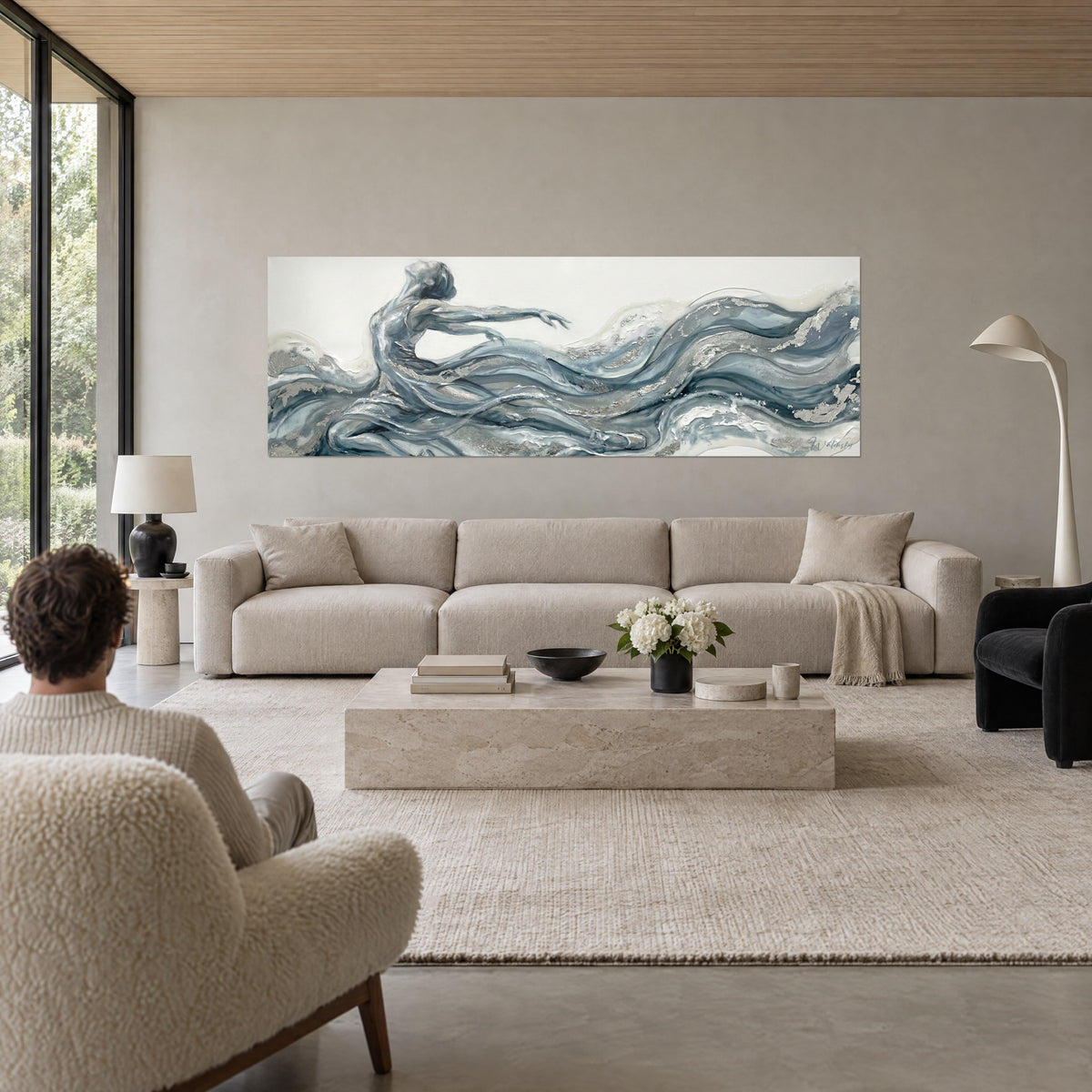 Wall art dancer with open arms, flowing blue-grey drapery and silver reflections, above a sofa in a bright living room