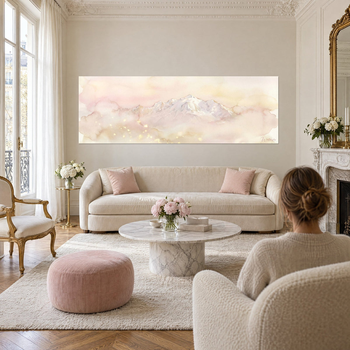 Cuadro macizo montaña nevada en acuarela rosa y oro, brumas pastel, pareja de espaldas sobre un sofá en un salón luminoso