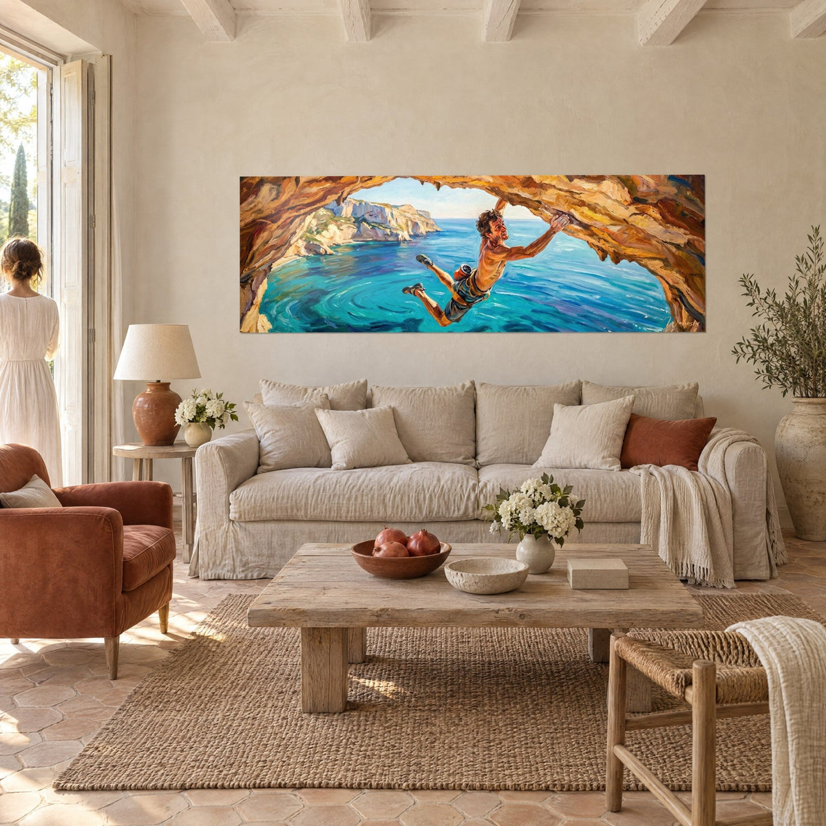 Gemälde eines oberkörperfreien Kletterers, unter einem ockerfarbenen Felsgewölbe hängend, türkisfarbenes Meer und weiße Felswand, über einem Sofa in einem hellen Wohnzimmer