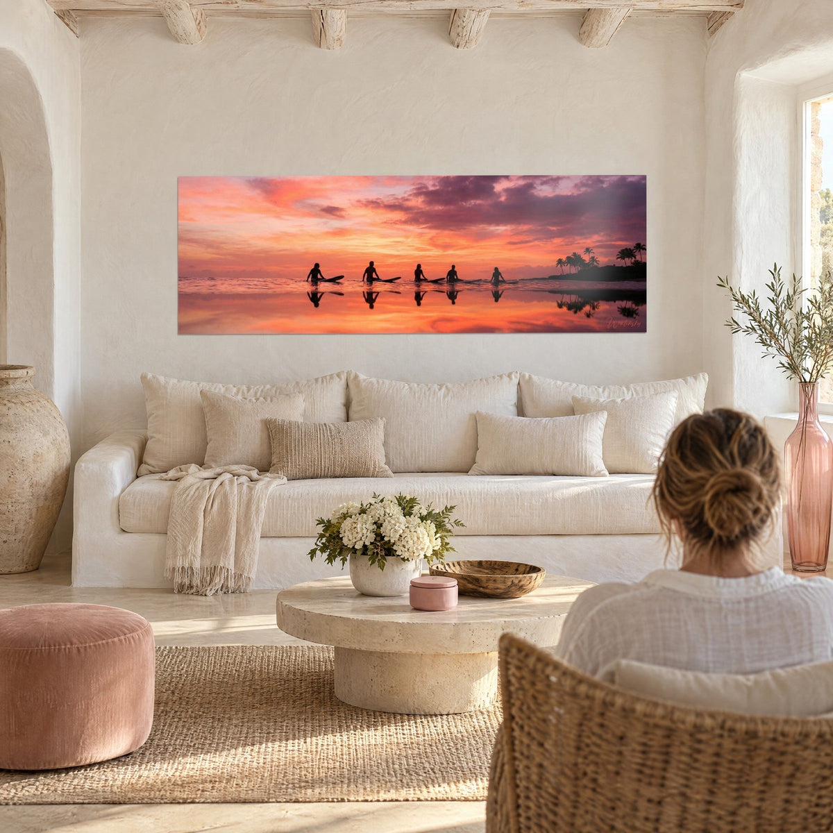 Cuadro cinco surfistas sentados sobre sus tablas, cielo naranja y violeta, reflejos en el agua, encima de un sofá en un salón luminoso