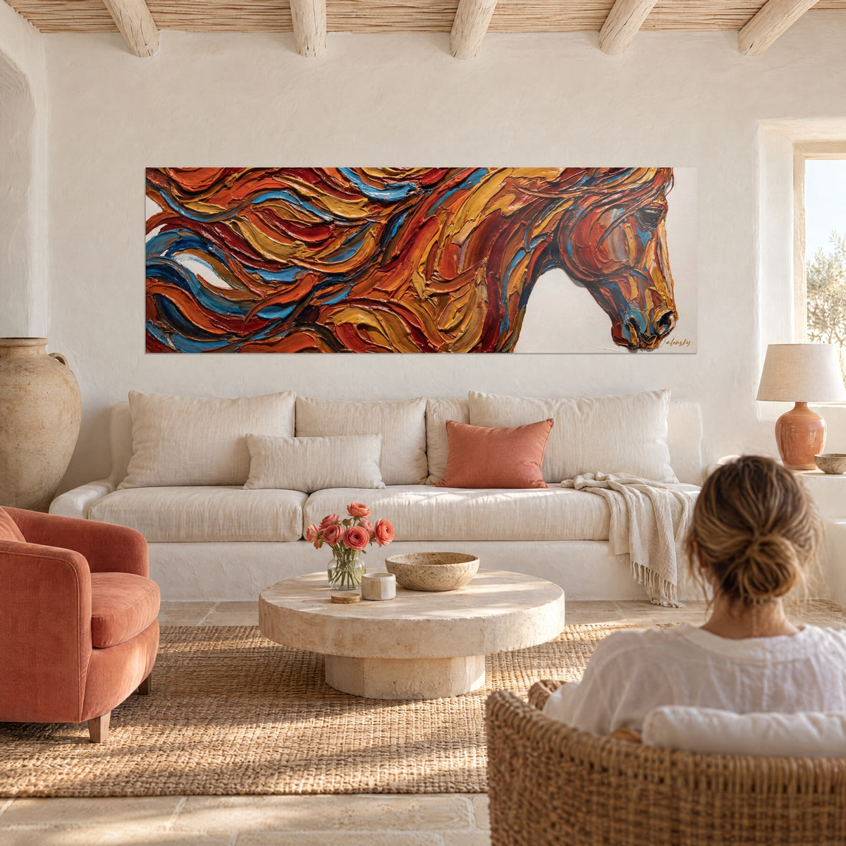 Cuadro caballo abstracto con crin naranja y azul en relieve, una mujer de espaldas sobre un sofá en un salón luminoso