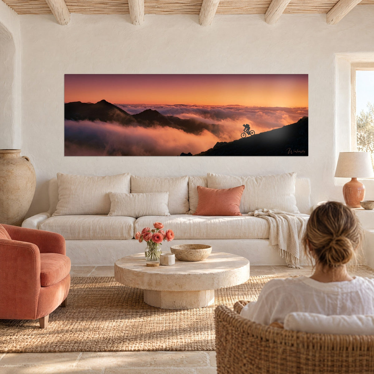 Gemälde Mountainbiker bei der Abfahrt über einen Grat über einem Meer aus orangefarbenen und rosa Wolken, Panorama, über einem Sofa in einem hellen Wohnzimmer