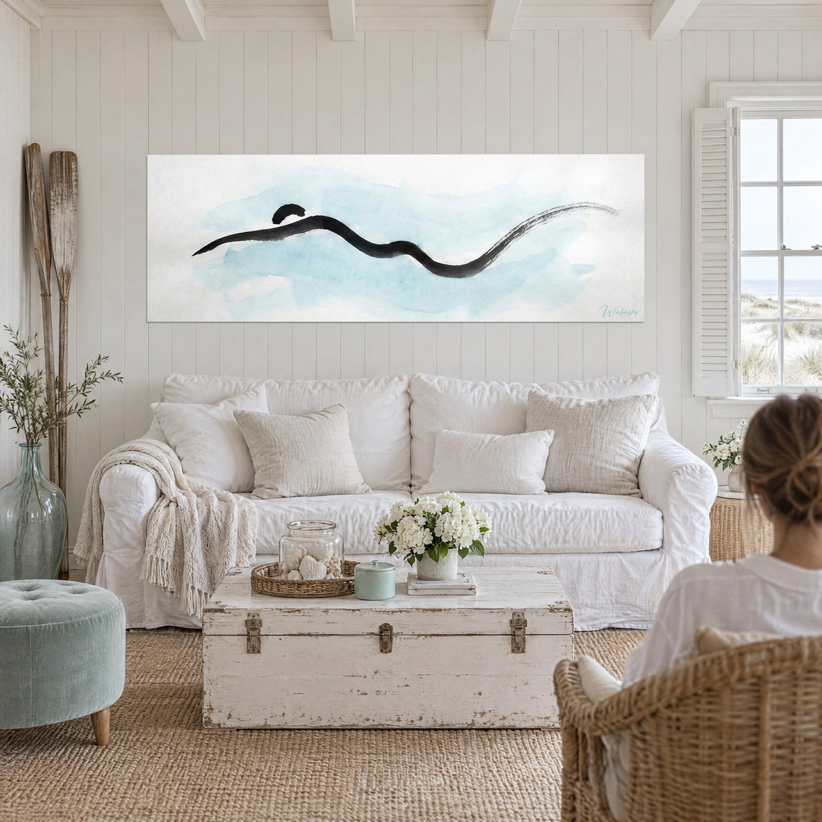 Tableau nageur minimaliste en trait d'encre noire sur lavis bleu ciel, sillage effilé, au-dessus d'un canapé dans un salon lumineux