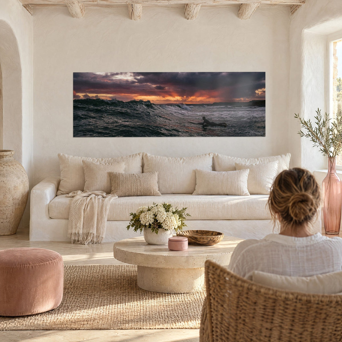 Gemälde Surfer liegend auf seinem Brett vor einem orangefarbenen und purpurnen Himmel, über einem Sofa in einem hellen Wohnzimmer